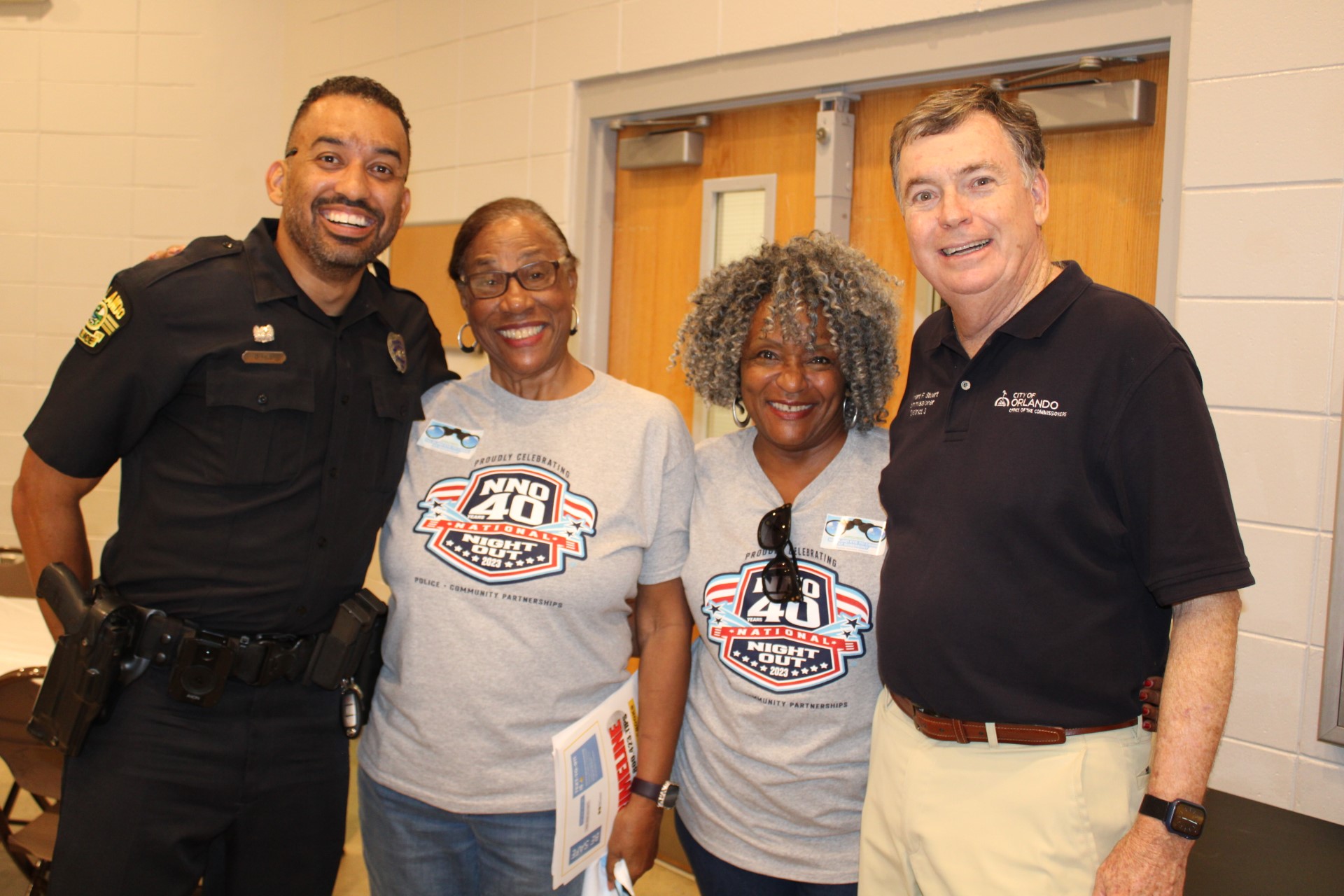 District 3 Commissioner Robert F. Stuart and an OPD Officer posing with two city residents at an NNO Block Party