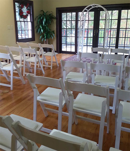 Summerlin rooom at Eola House setup for a wedding with white chairs and an arch in front of the patio doors.