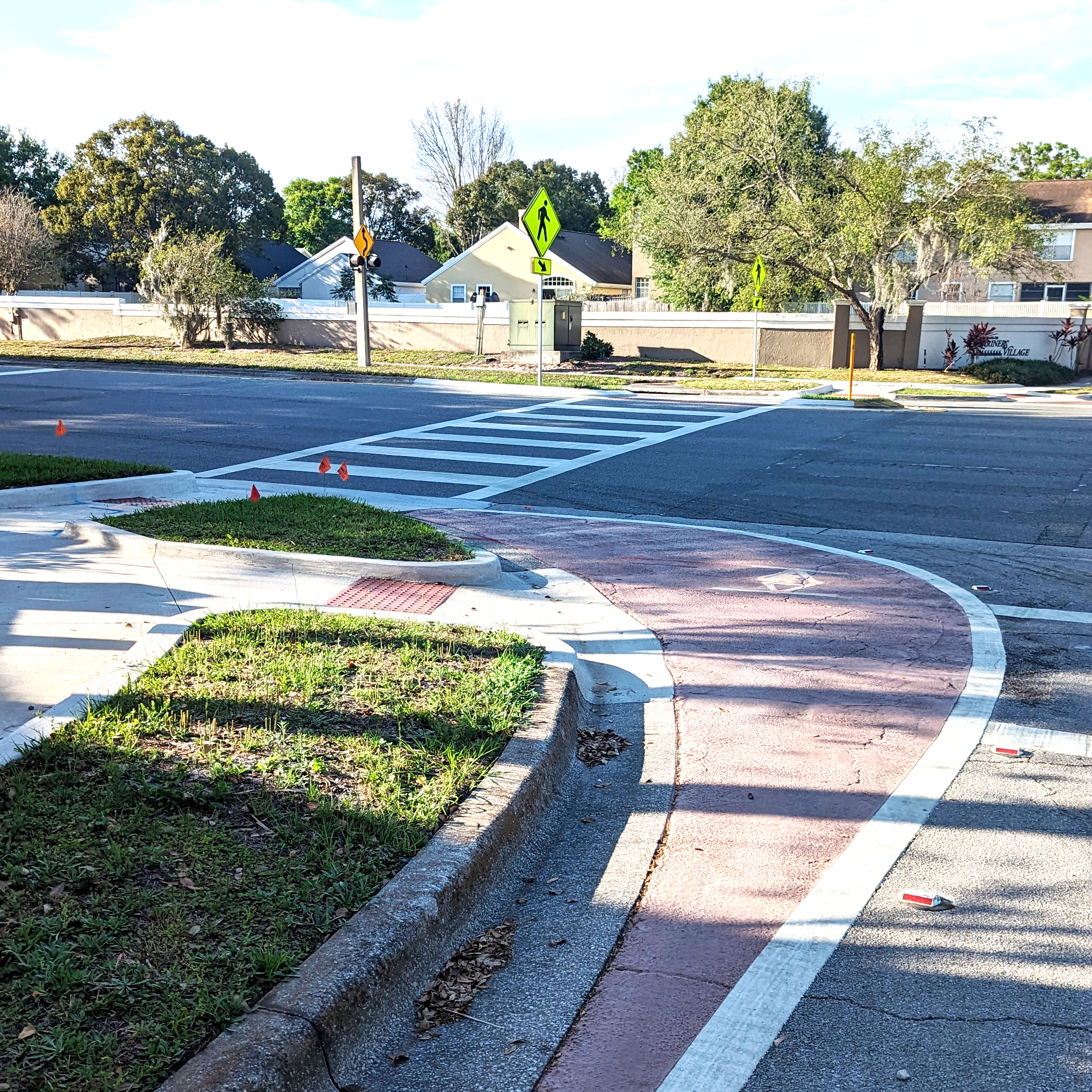 A photograph of a quick-build curb extension delineated by striping and red pavement coloring.