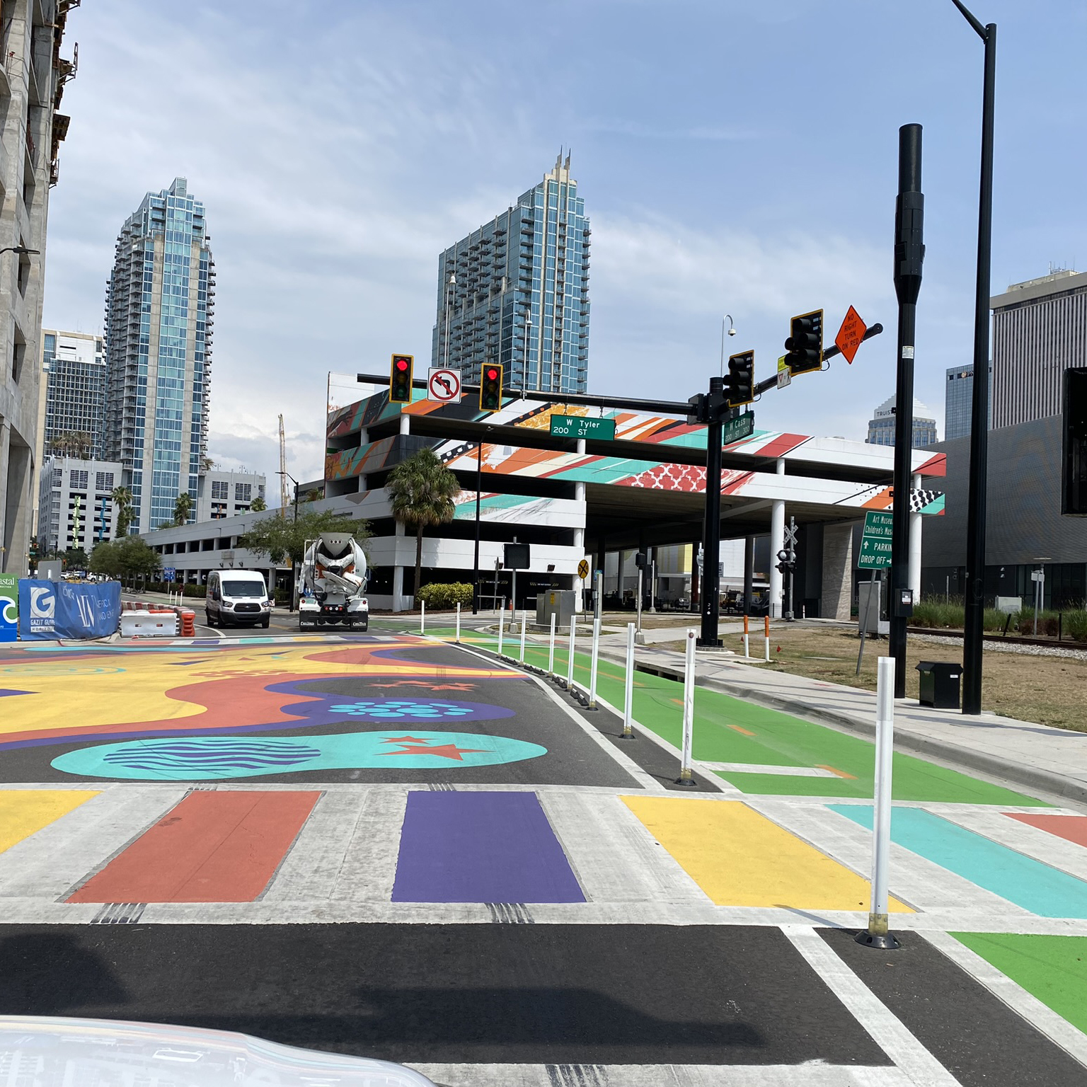 A photograph of a ladder crosswalk with colorful paint in between the typical white stripes.