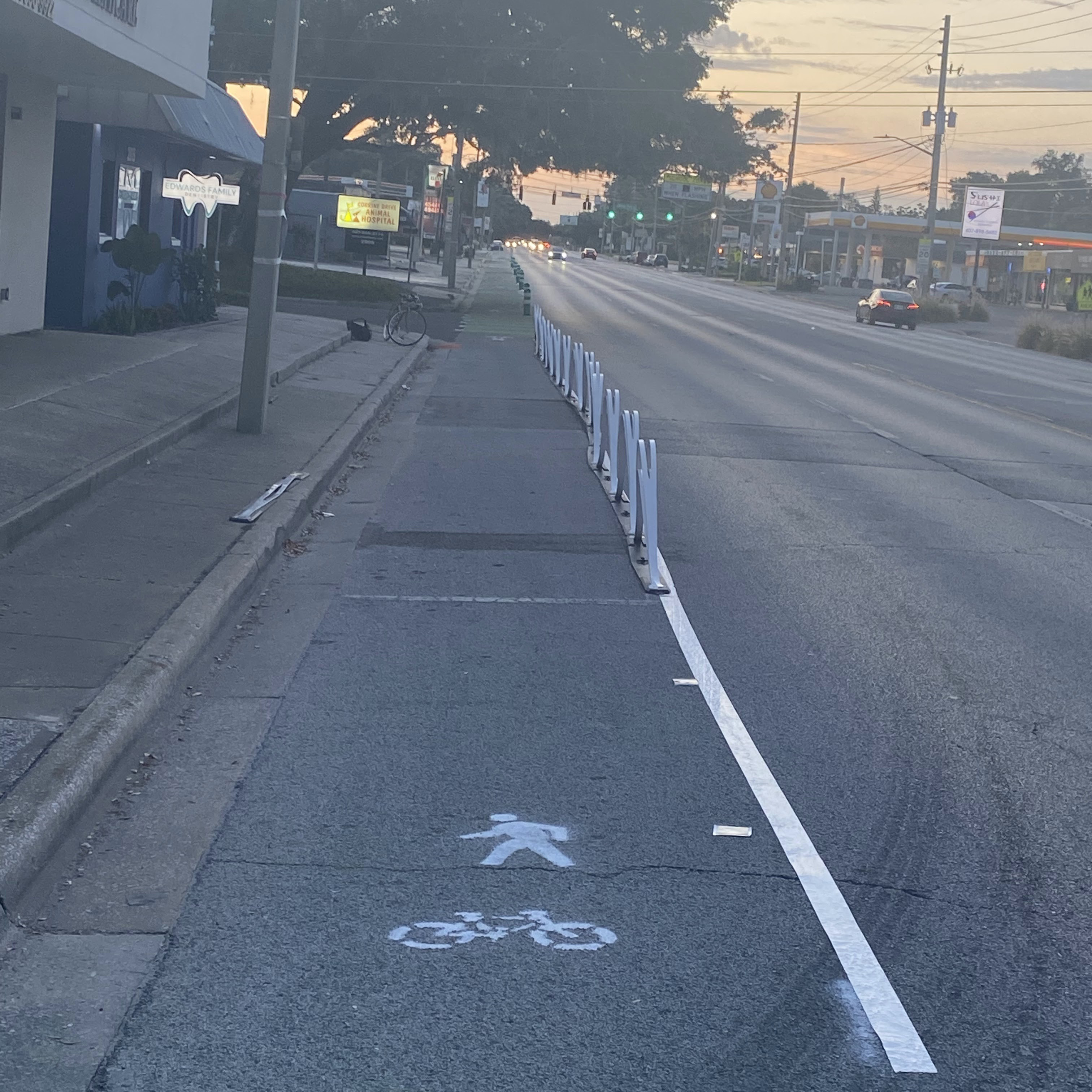 A photograph of a quick-build bicycle lane demarcated by traffic tape and flex posts.