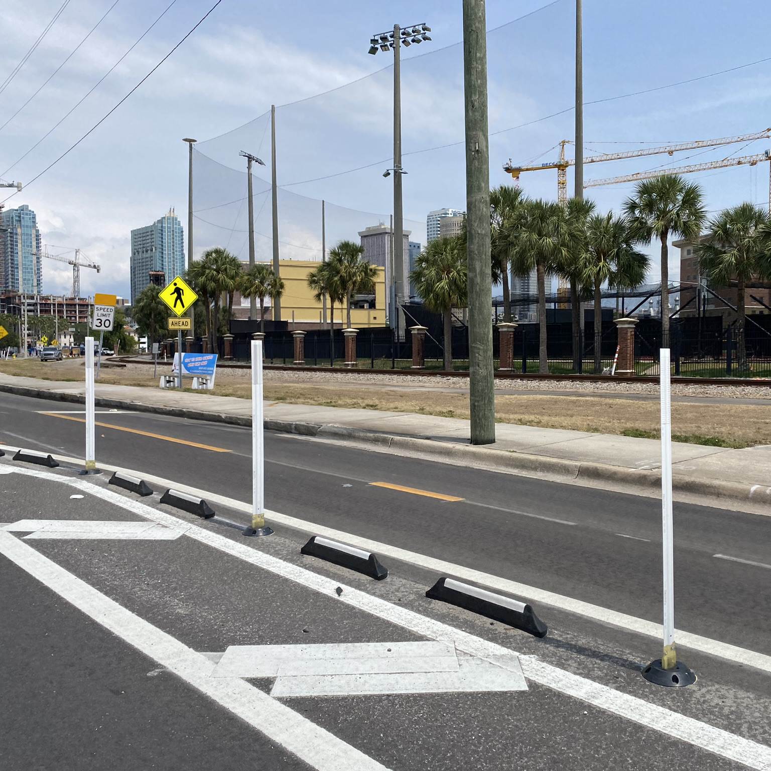 A photograph of a quick-build two-way bicycle lane delineated by flex posts and quick build parking stops.