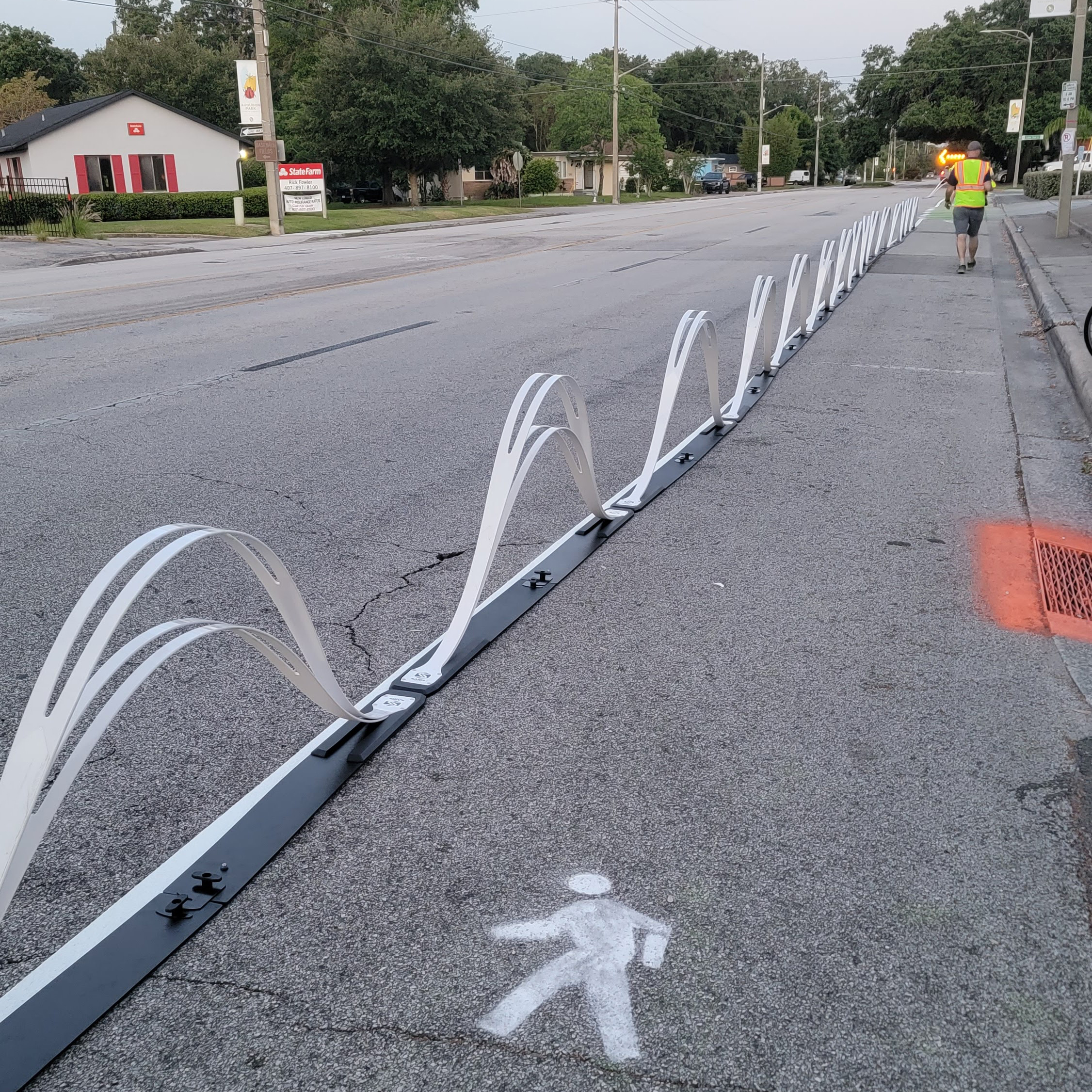 Delineators shaped like waves - or camel humps - separate a repurposed travel lane for people walking from vehicle traffic.