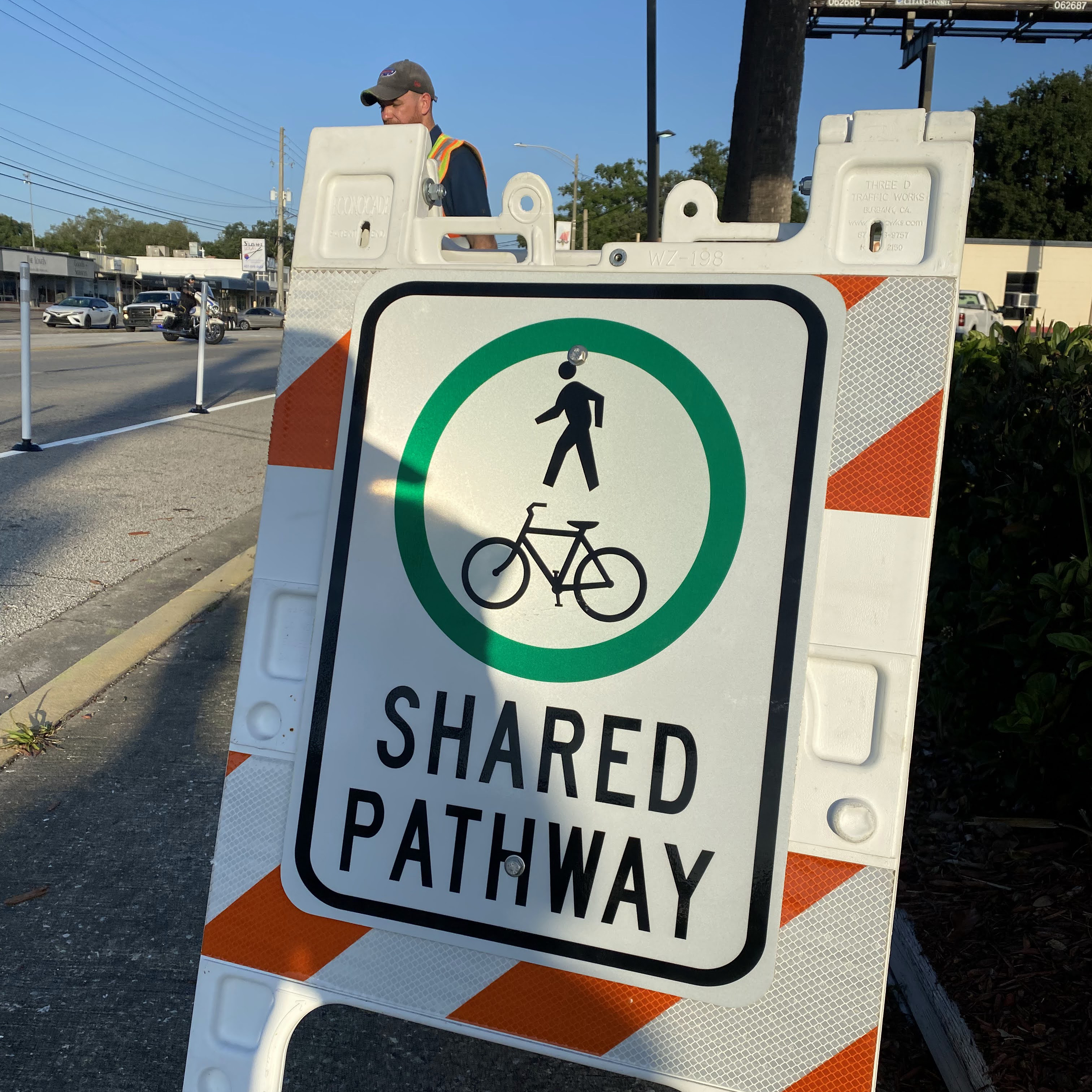 An sign reading Shared Pathway with the picture of a person and a bike is affixed to an A-frame.